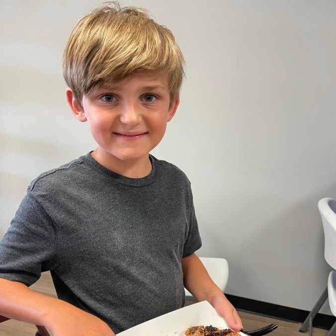 A young boy holding a plate of food with a fork