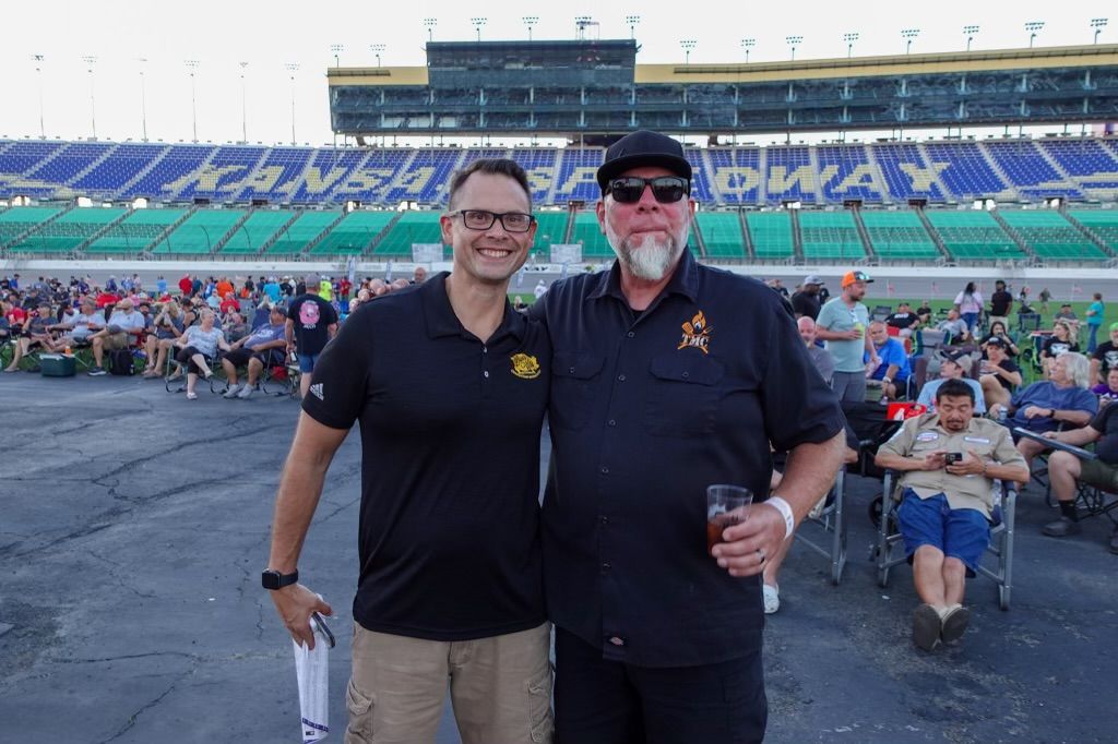 Two men are posing for a picture in front of a stadium.