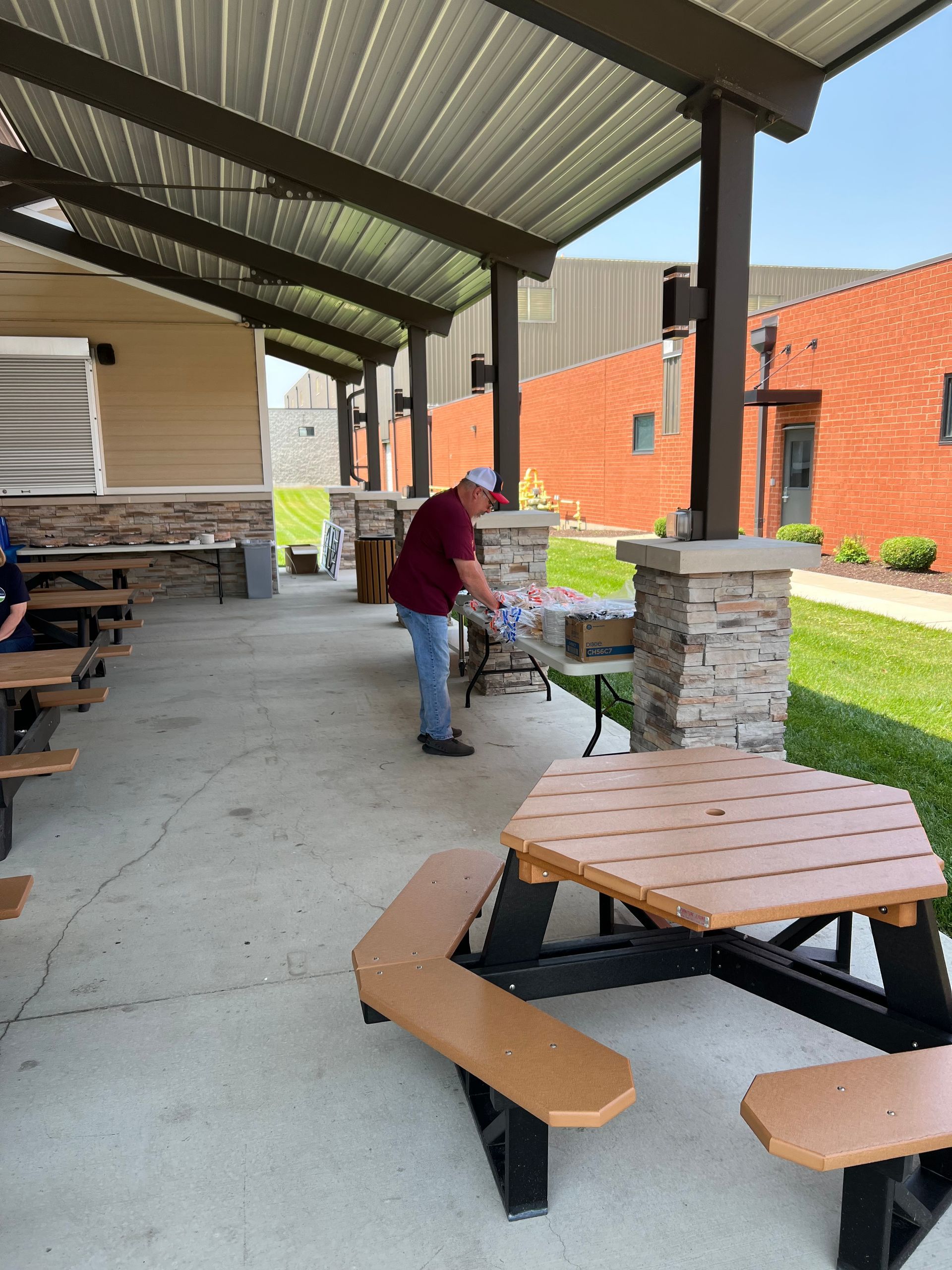 A man is standing next to a picnic table under a canopy.