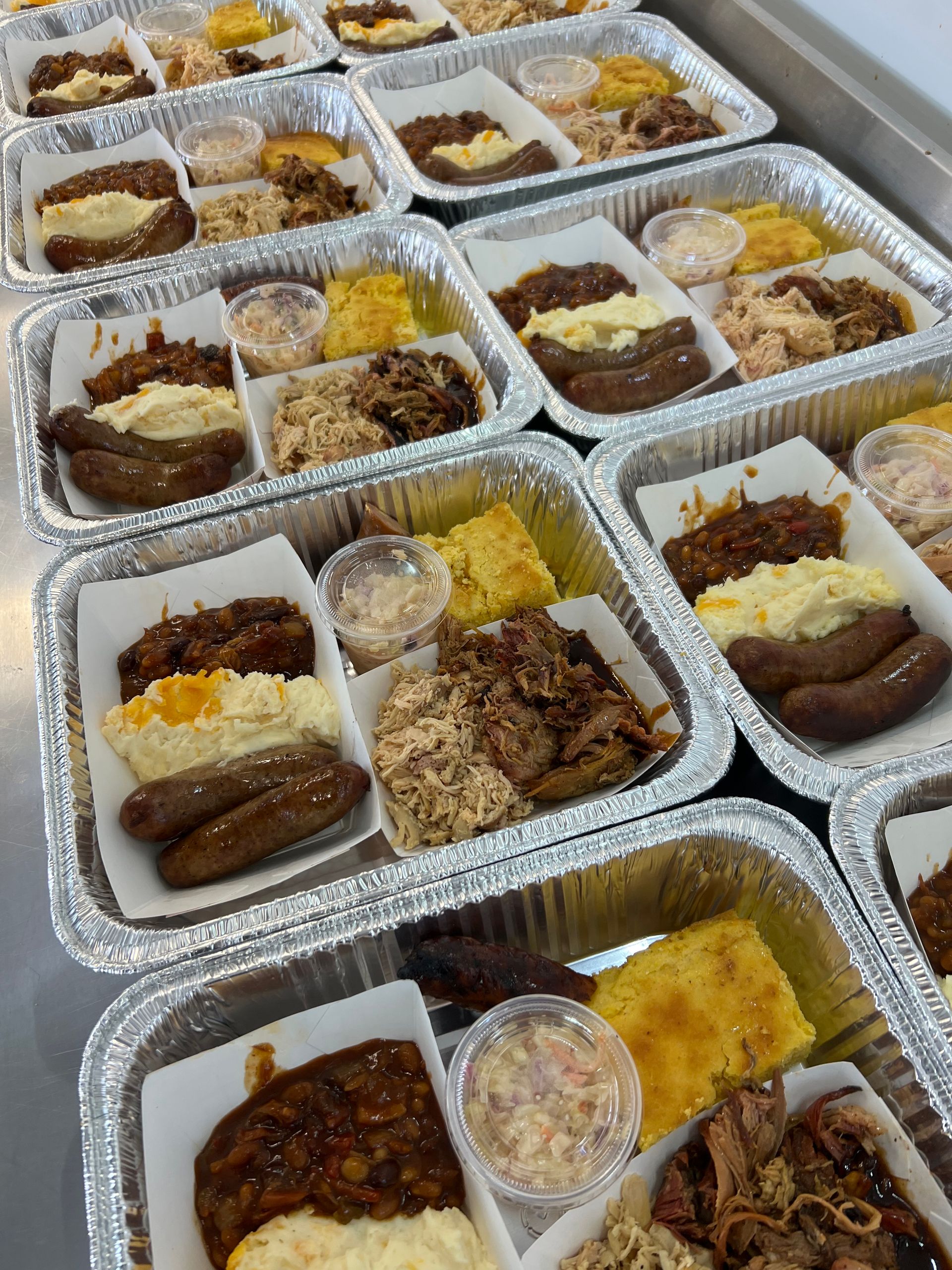 A bunch of trays of food are sitting on a table.