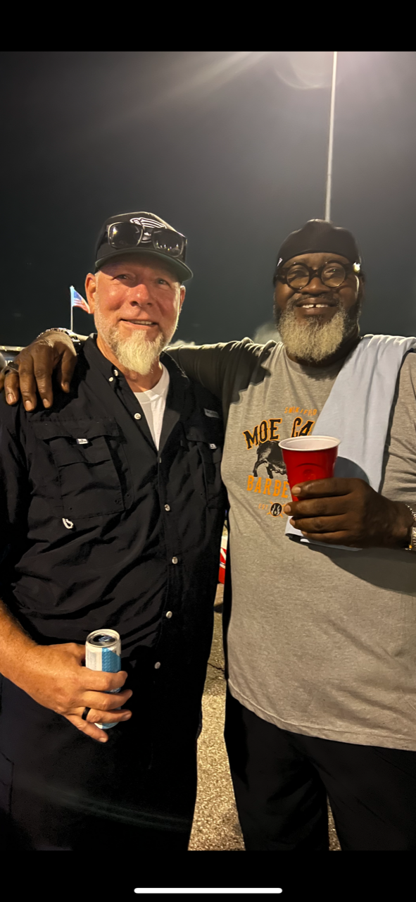 Two men are standing next to each other on a football field.