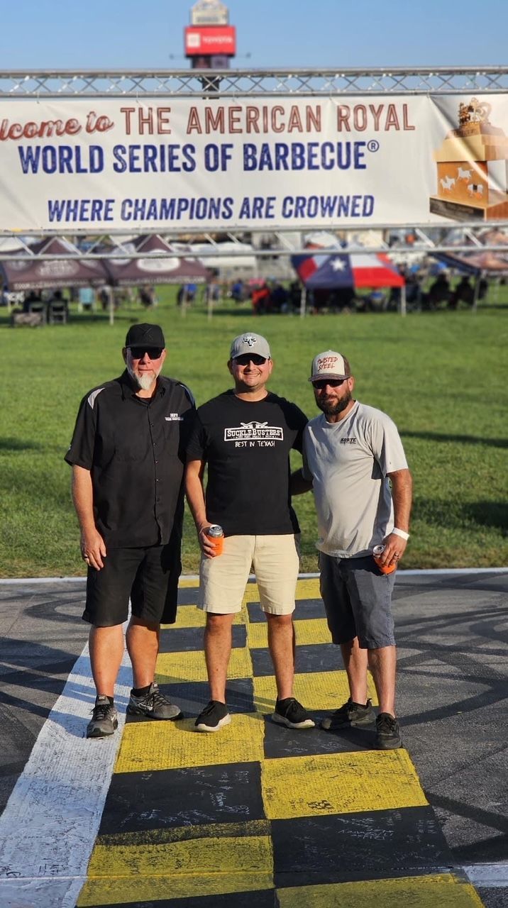 Three men are standing in front of a sign that says welcome to the american royal world series of barbecue where champions are crowned.