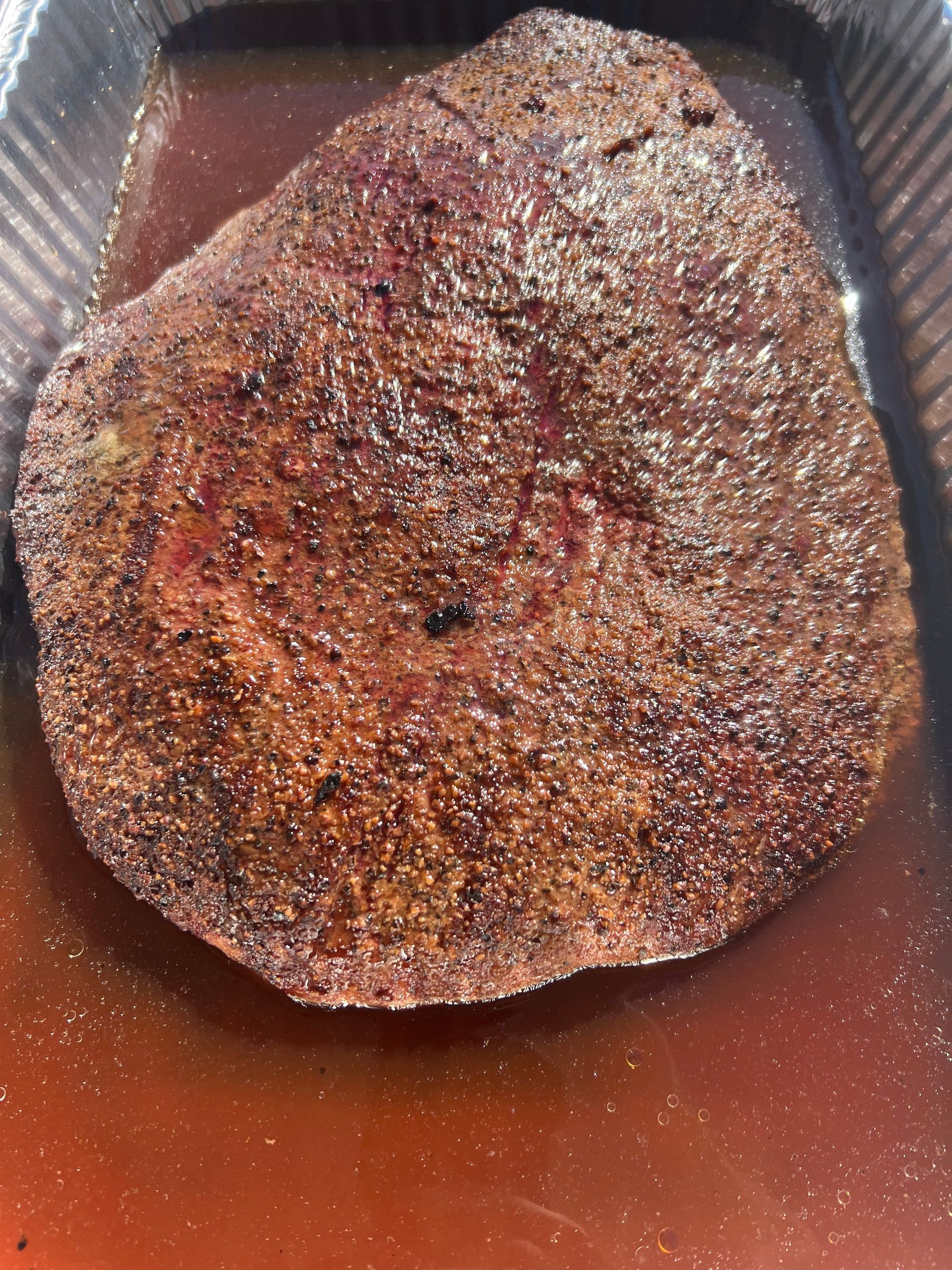 A large piece of meat is sitting in a pan of liquid.
