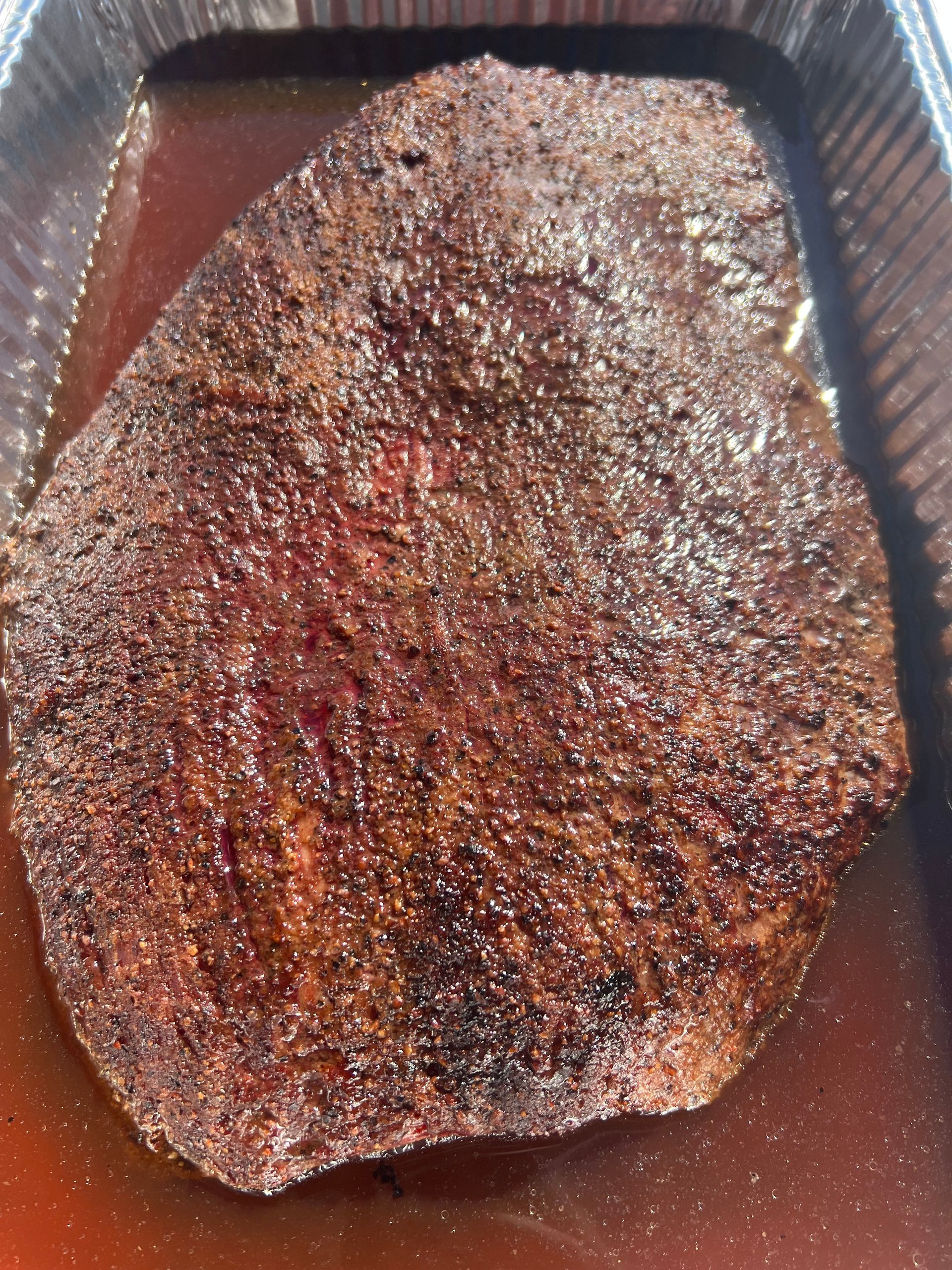 A large piece of meat is sitting in a pan of liquid.