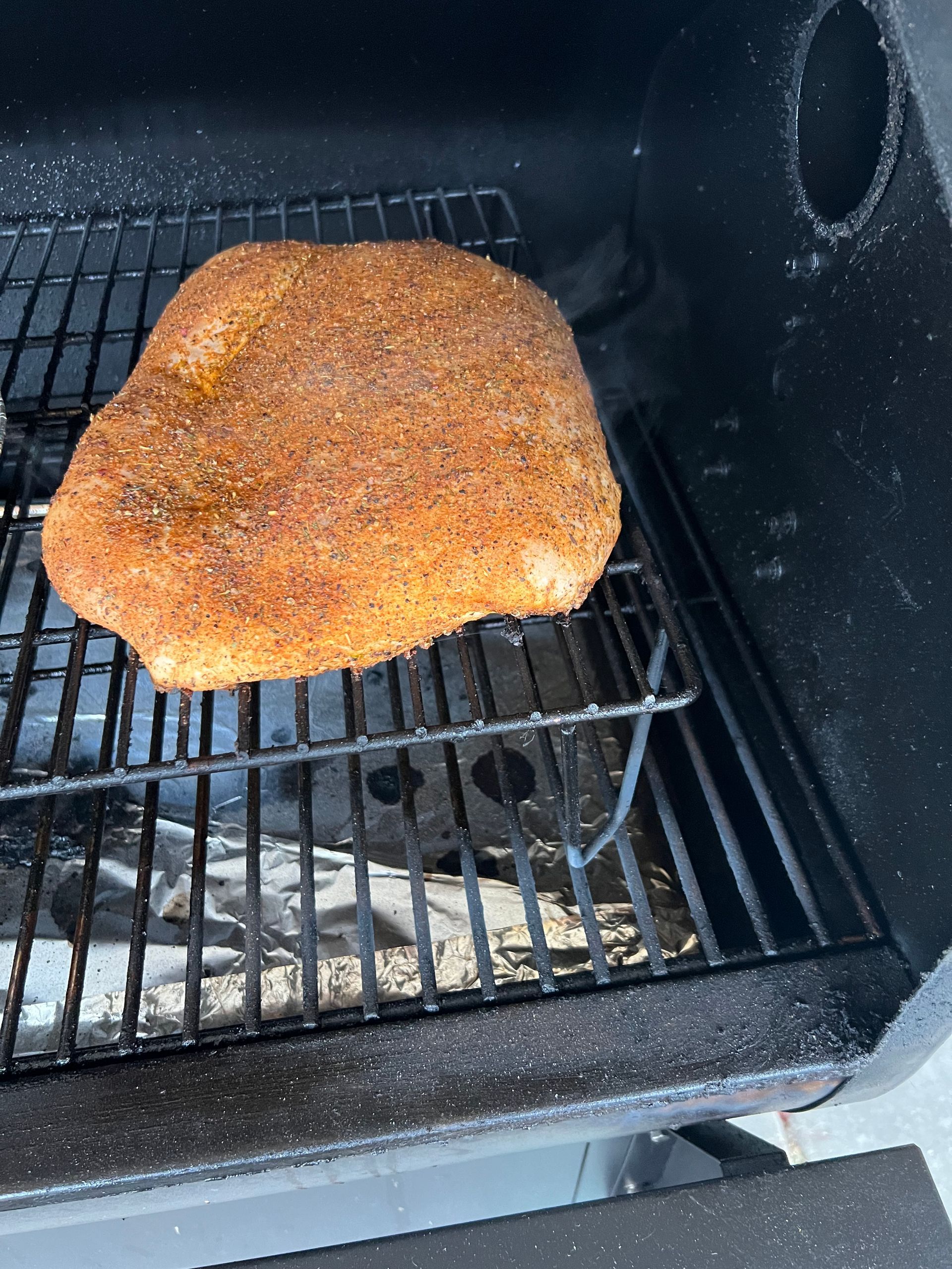 A large piece of meat is cooking on a grill.