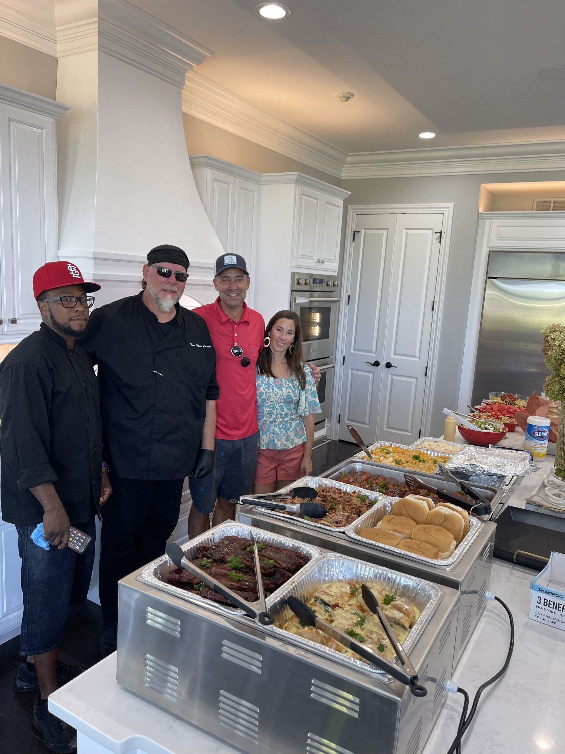 A group of people standing around a buffet table in a kitchen.