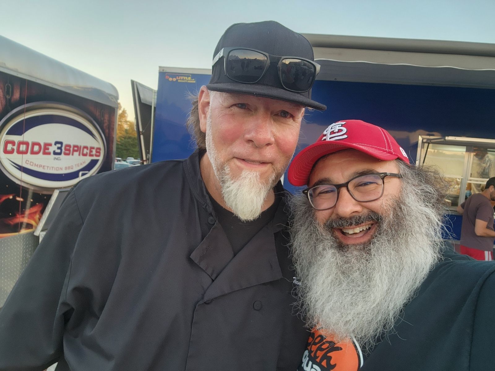 Two men are posing for a picture in front of a food truck that says code space