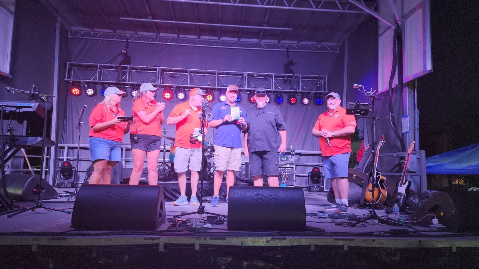 A group of people are standing on a stage talking into microphones.