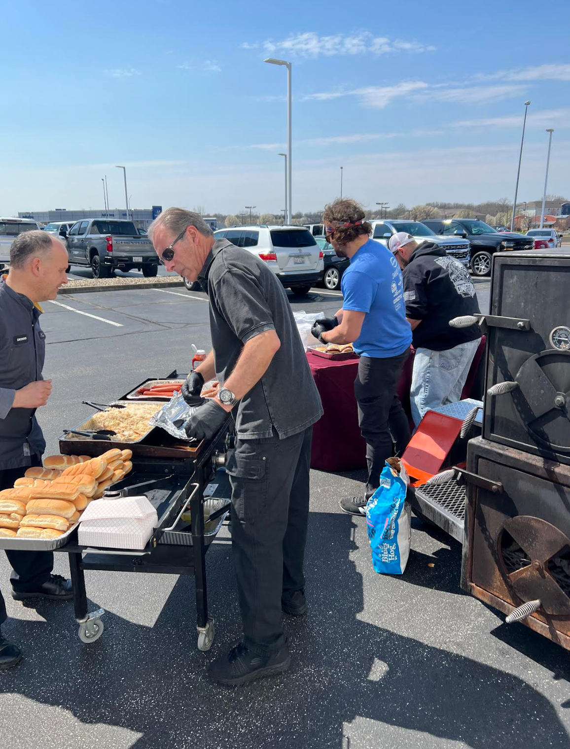 A group of men are preparing food in a parking lot.
