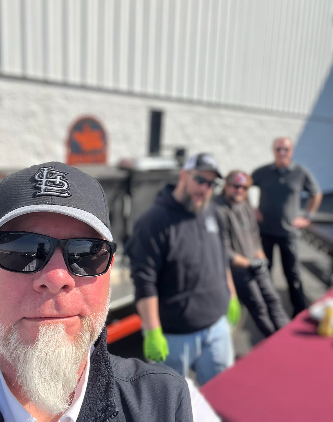 A man with a beard is taking a selfie in front of a car.
