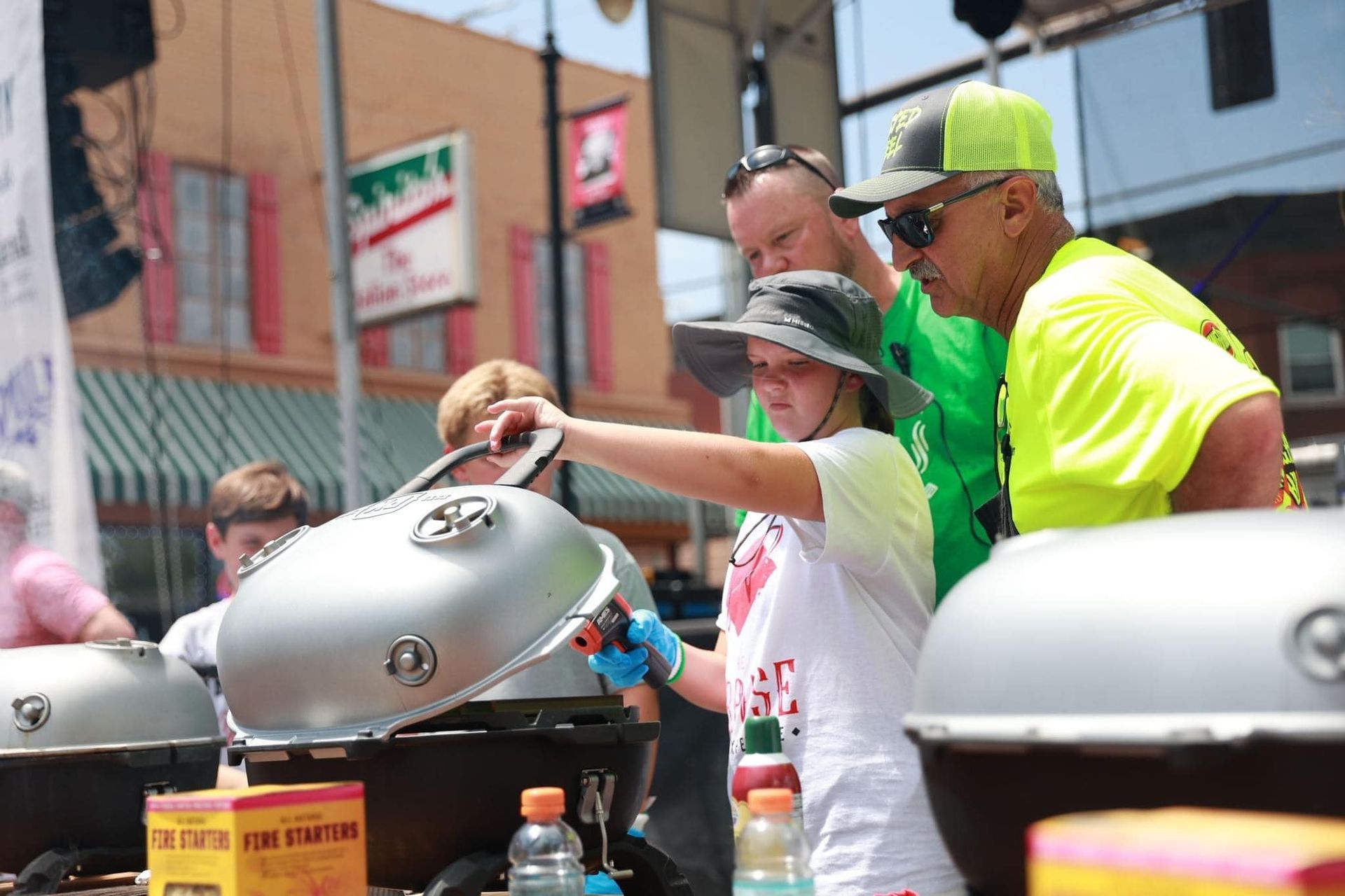 A group of people are standing around a grill.