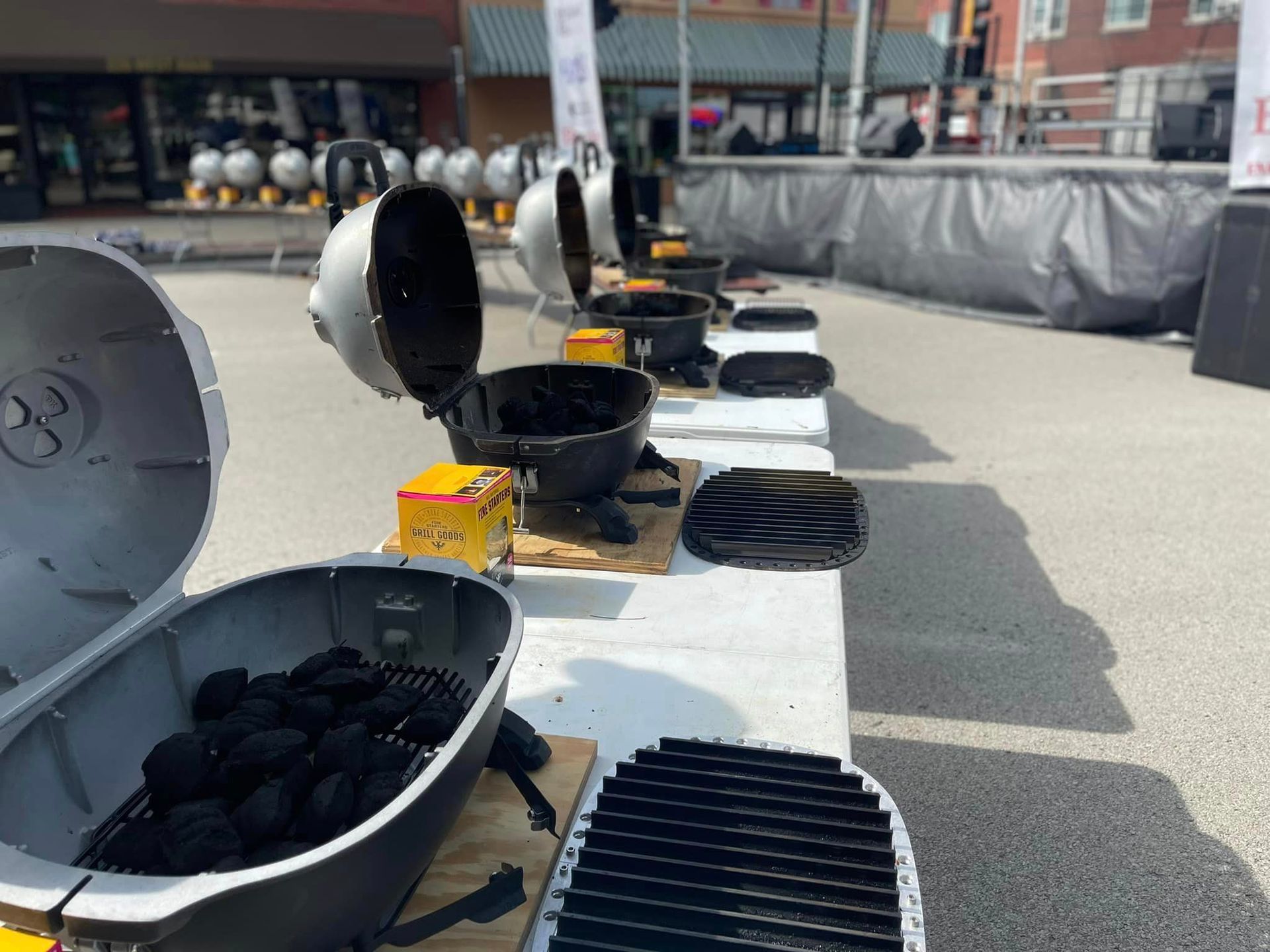 A row of grills are lined up on a table outside.