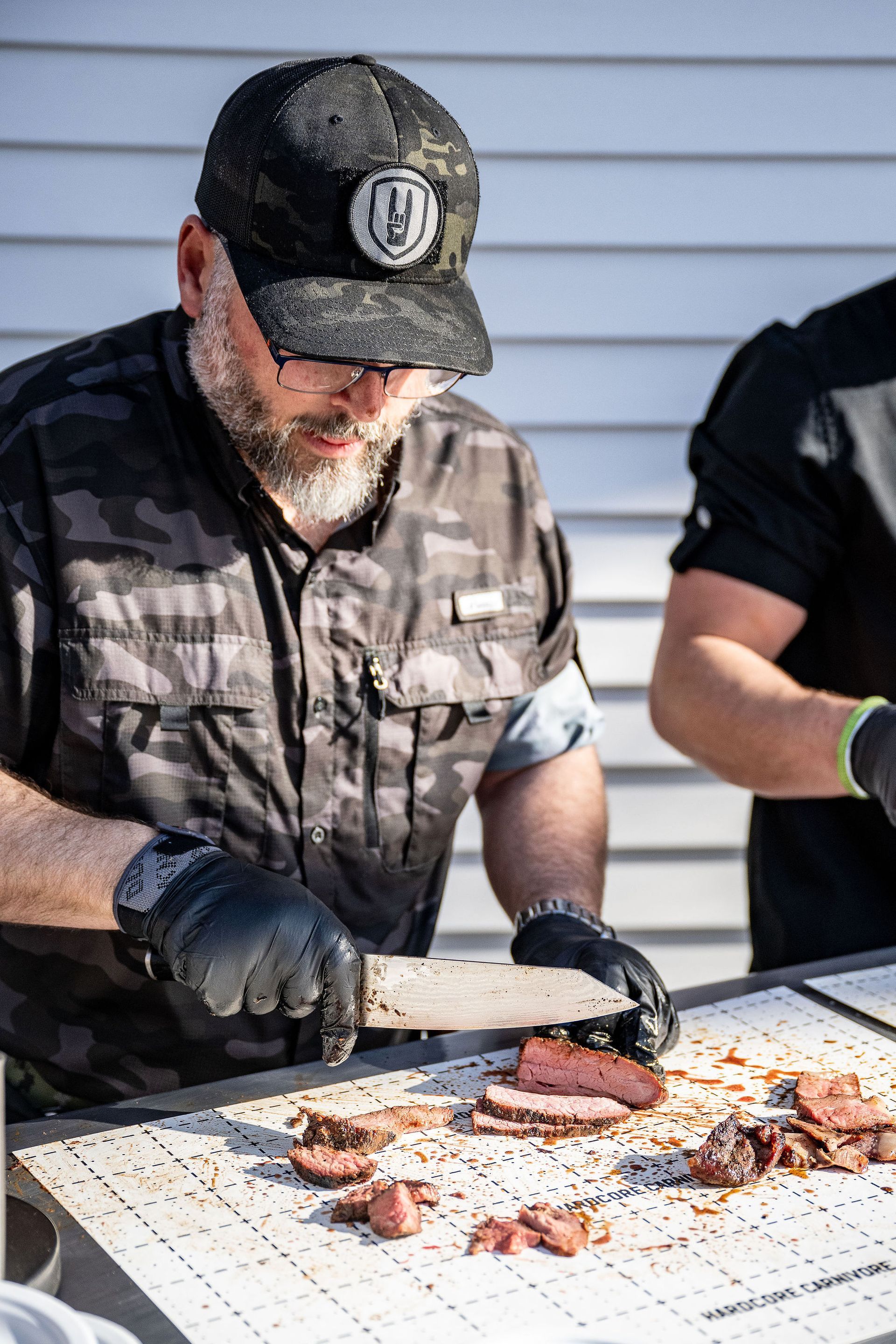 A man is cutting a piece of meat on a table.