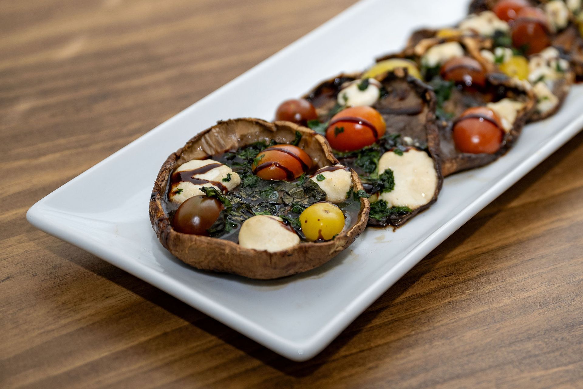 A white plate topped with mushrooms and tomatoes on a wooden table.