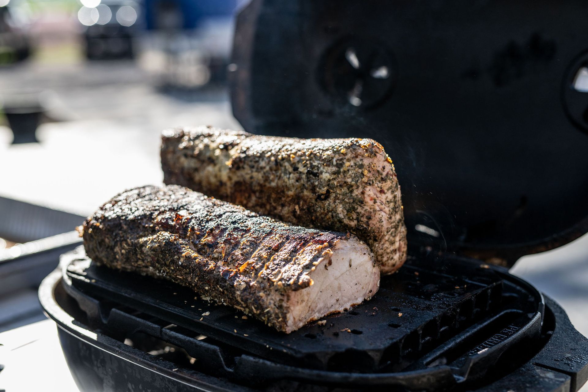 Two pieces of meat are cooking on a grill.