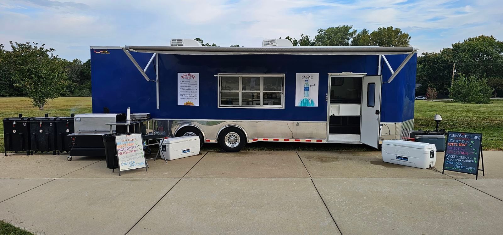A blue and silver food truck is parked on the side of the road.