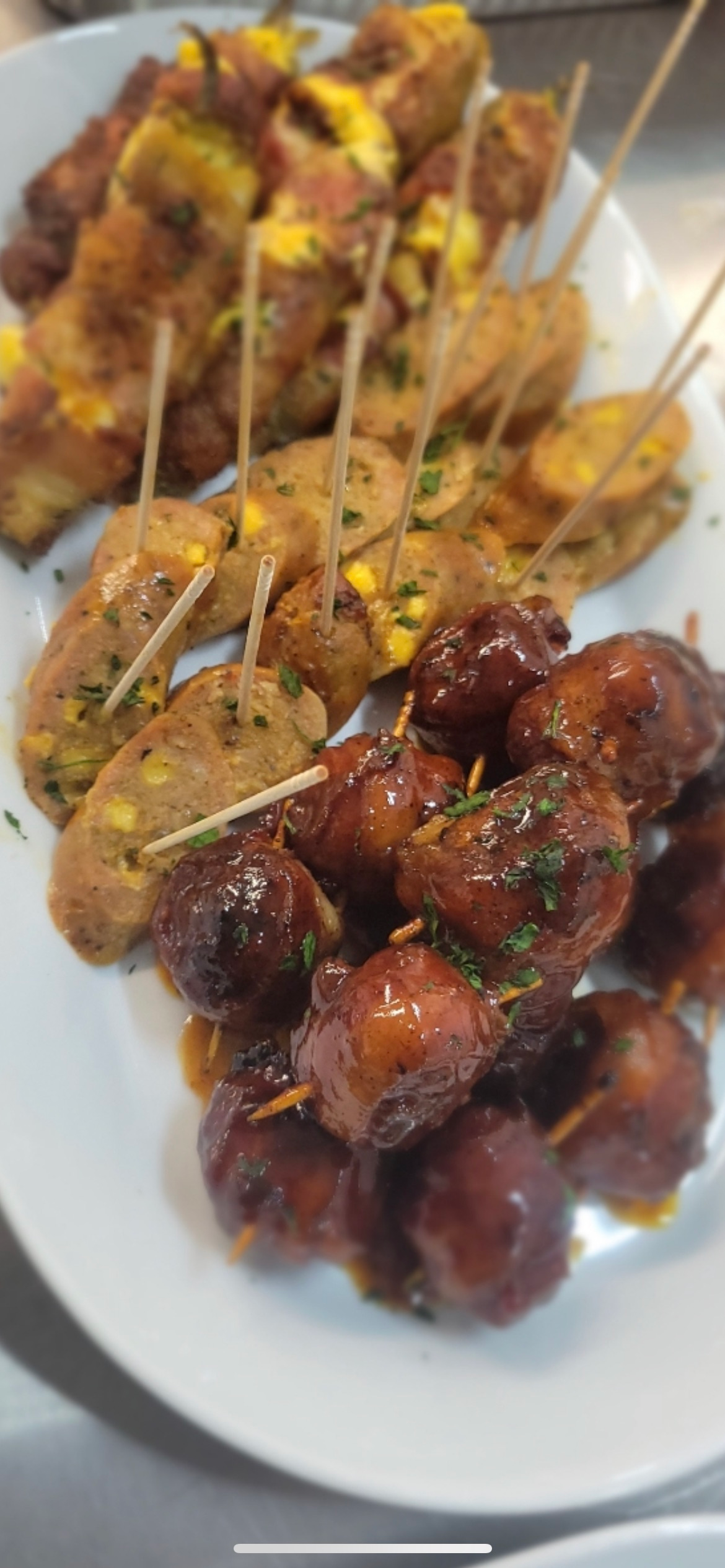 A white plate topped with a variety of food on sticks.