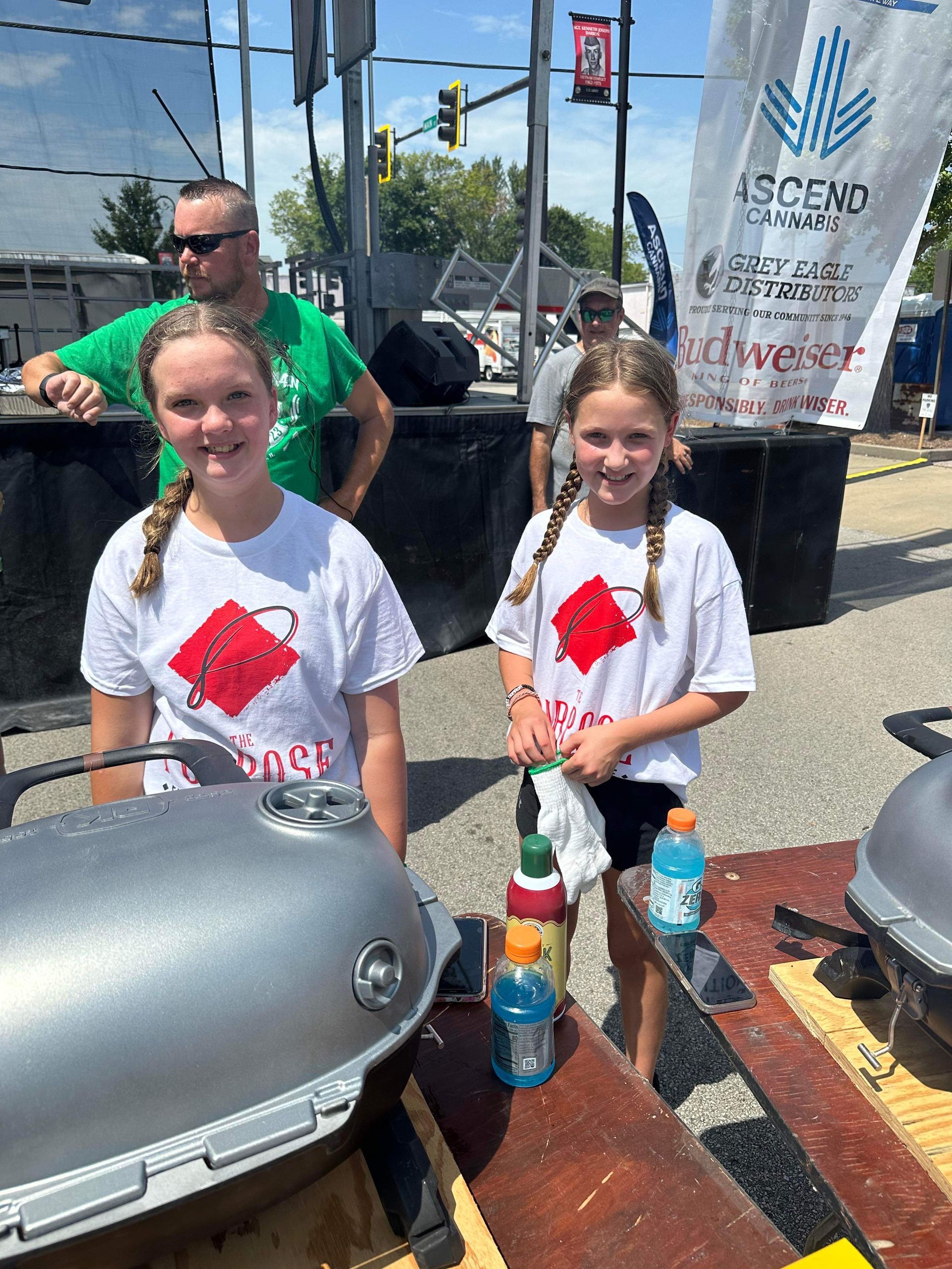 Two young girls are standing next to each other in front of a grill.