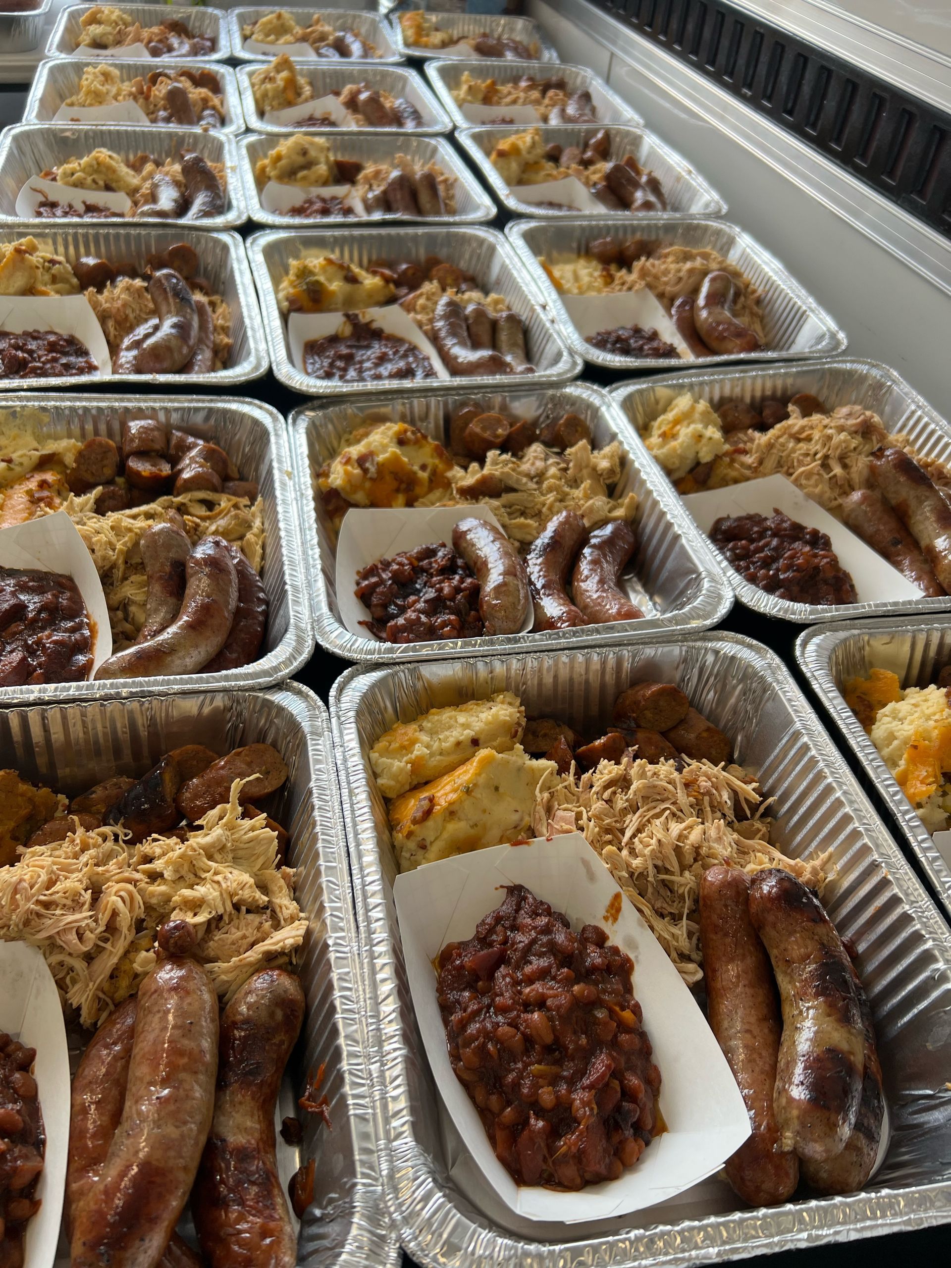 A bunch of aluminum foil containers filled with food on a table.