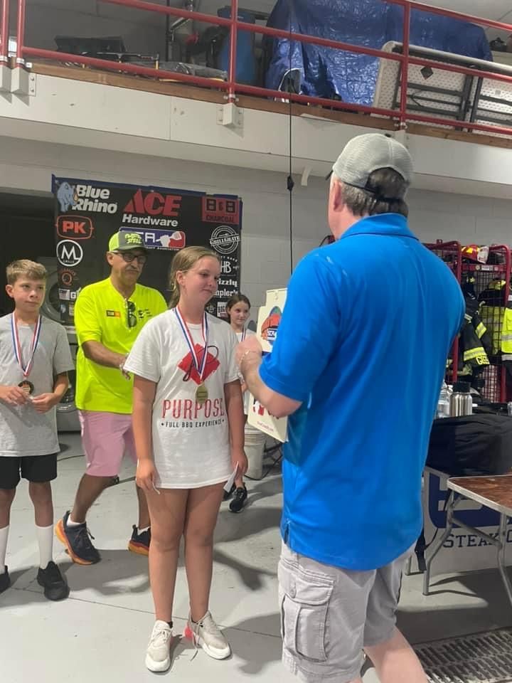 A man in a blue shirt is giving a medal to a girl in a white shirt.