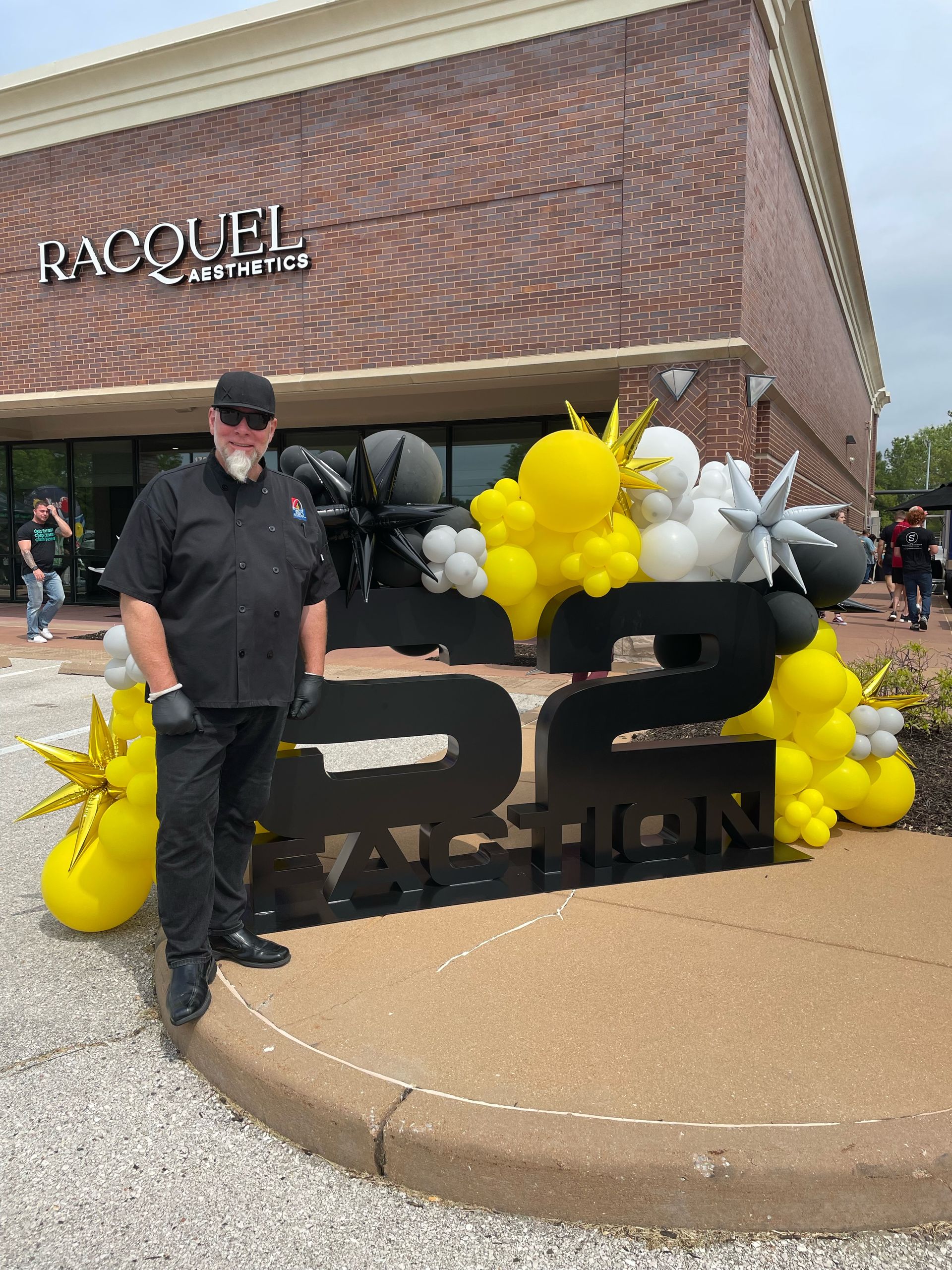 A man is standing in front of a building decorated with balloons.