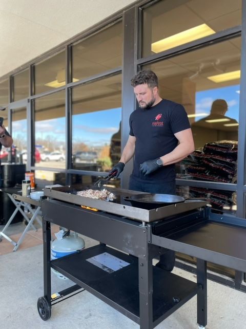 A man is cooking on a grill outside of a building