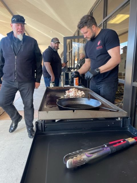 A man in a black shirt is standing next to a tray of food