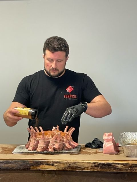 A man is pouring sauce on a pile of meat on a table.