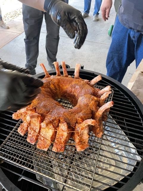 A person is cooking bacon and shrimp on a grill