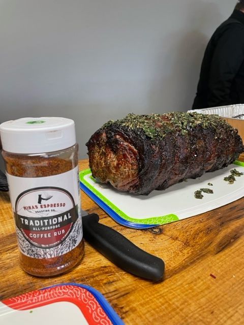A jar of traditional coffee rub next to a piece of meat on a cutting board