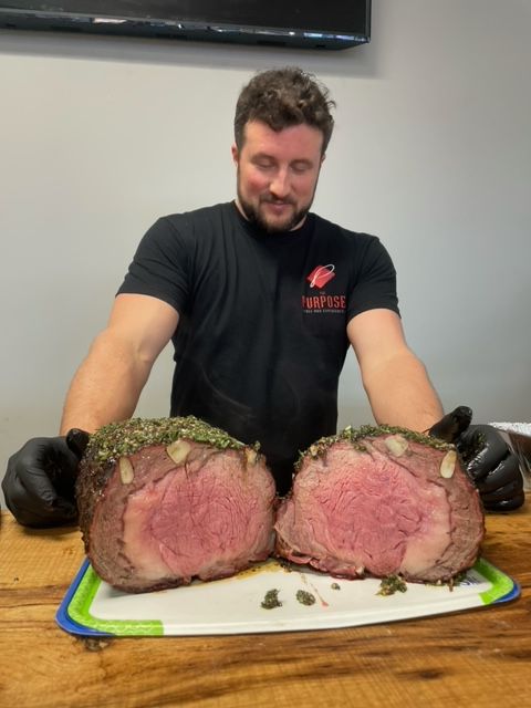 A man is holding a large piece of meat on a cutting board