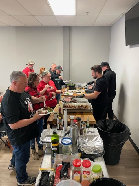 A group of people are standing around a table eating food.