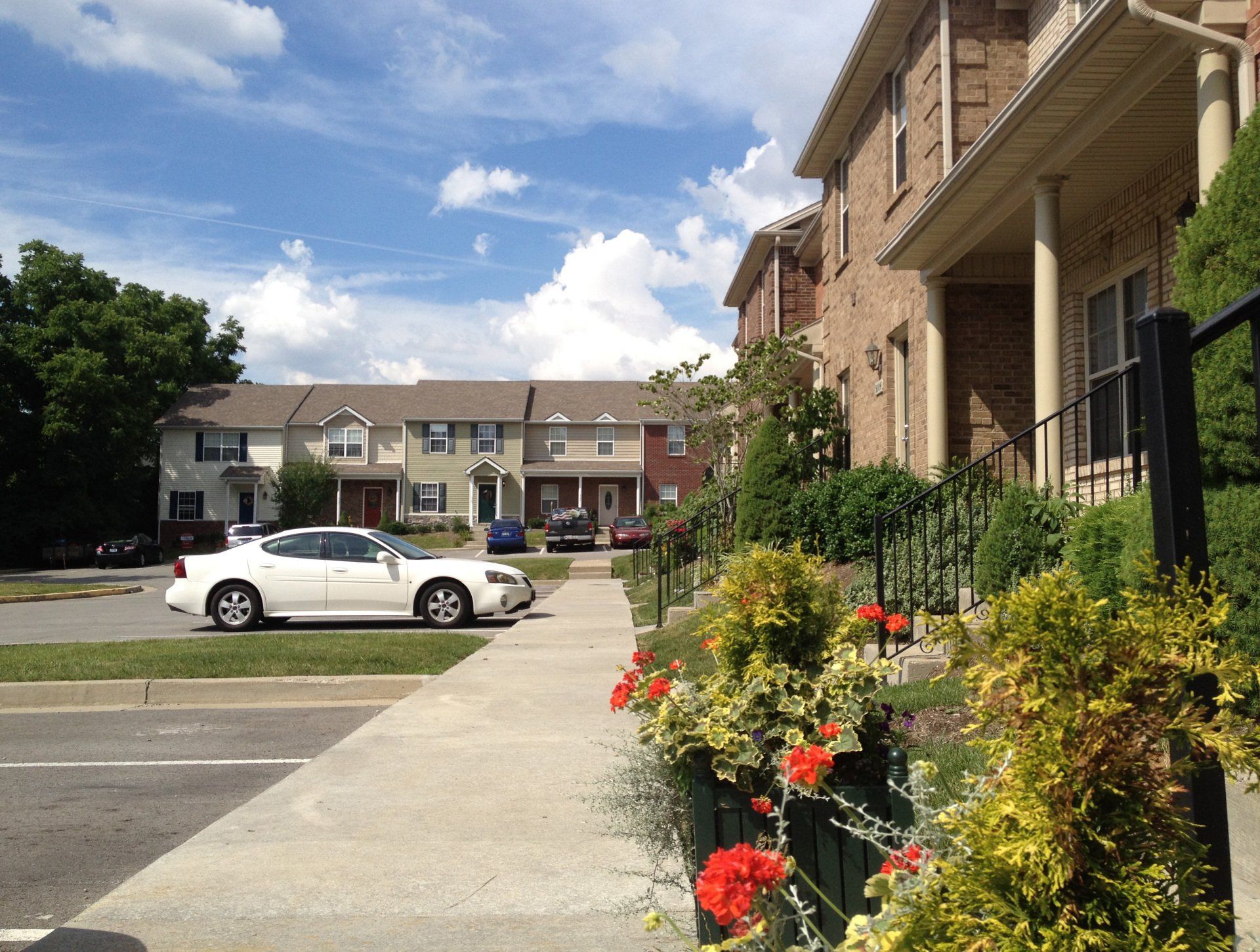 A white car is parked in front of a row of houses