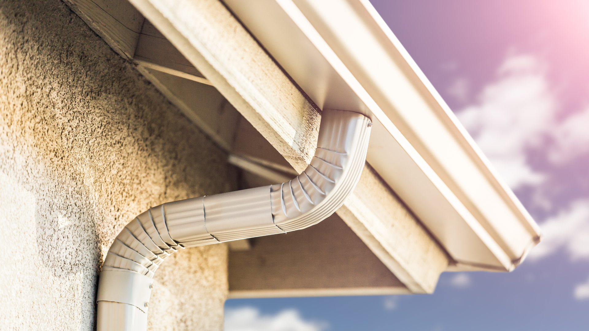 A close up of a white gutter on the side of a house.