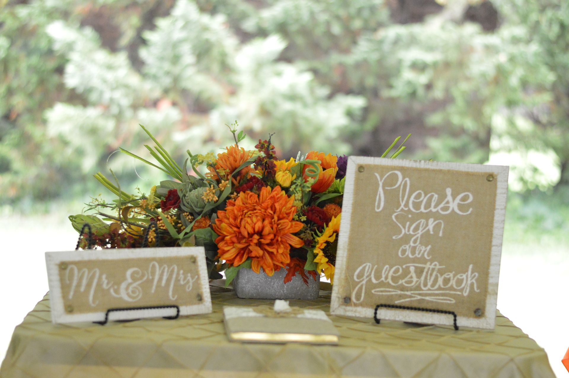 Wedding guest book table, orange floral arrangement, Mr. & Mrs. sign, and 