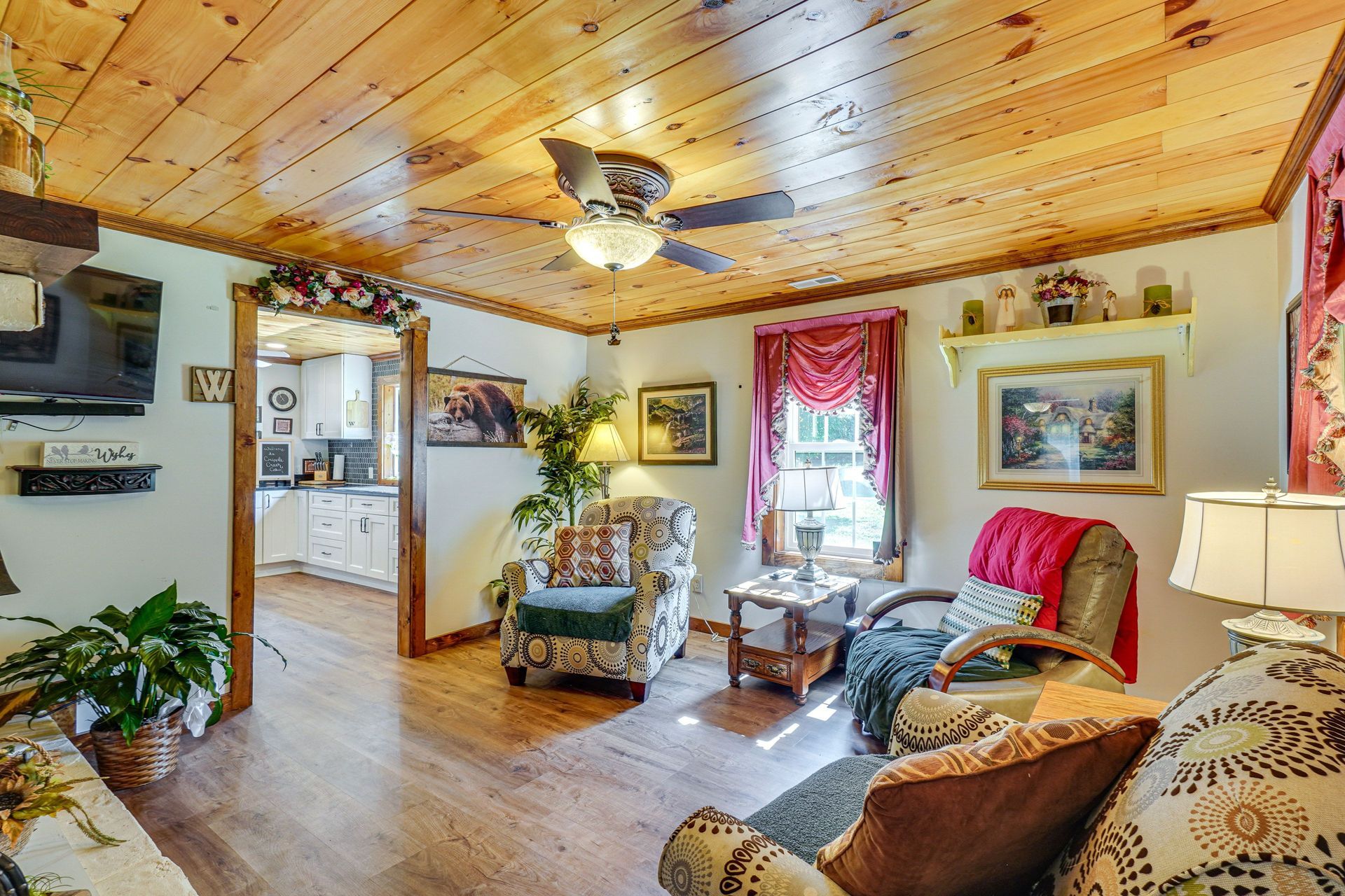A living room with a couch , chair , table and ceiling fan.