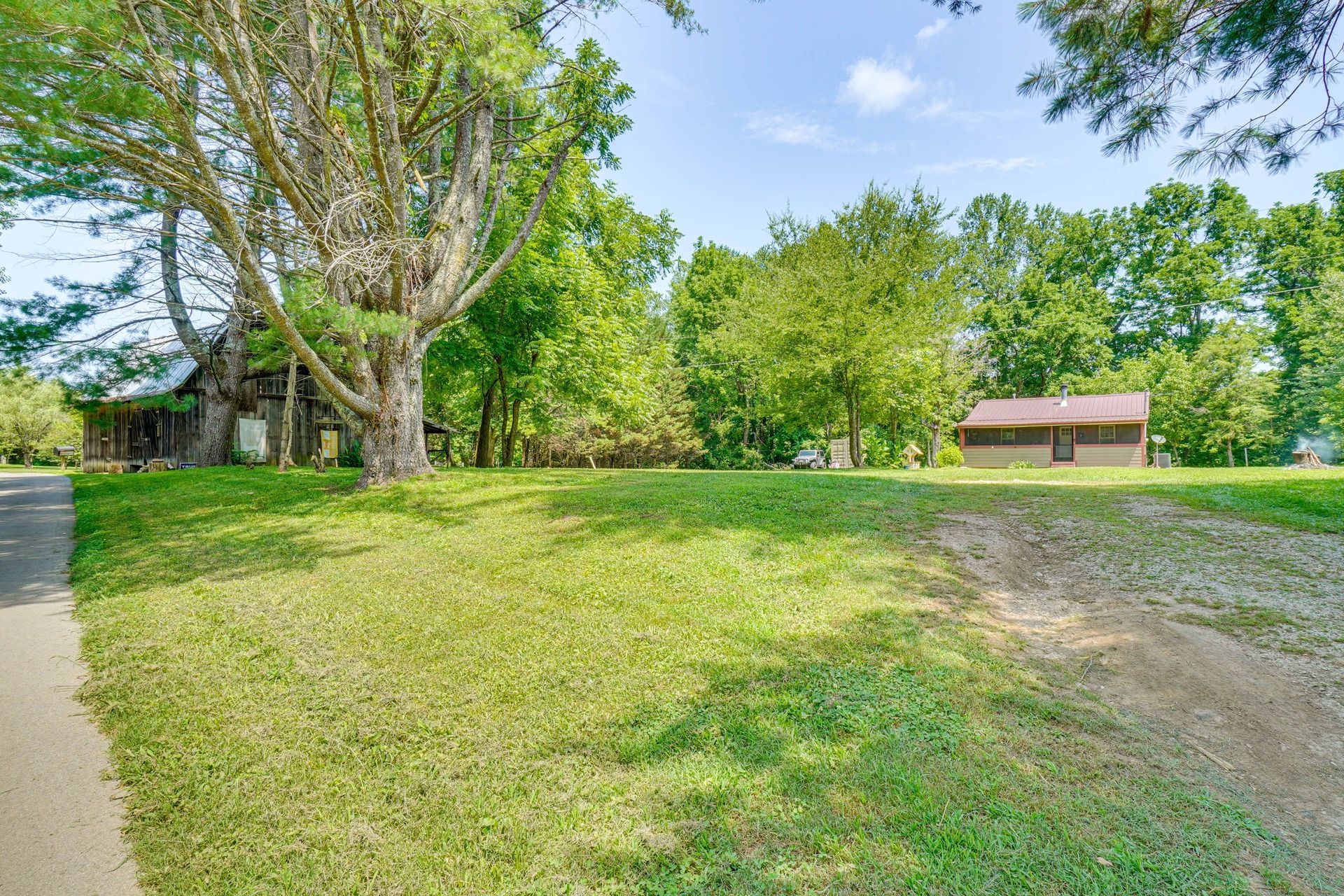 A house is sitting in the middle of a lush green field surrounded by trees.