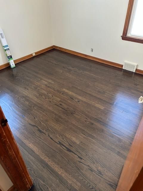 Dark wood flooring in a room with light walls and a window.