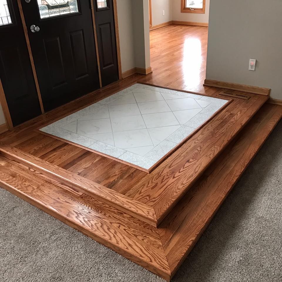 Entryway with hardwood steps, a tiled landing, and a dark front door.