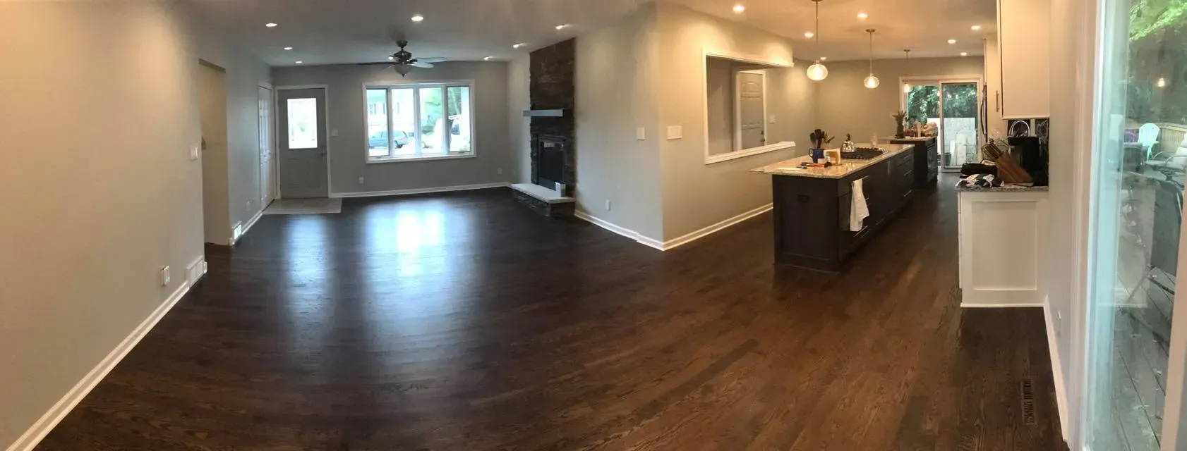 Spacious, open-concept living space with dark wood floors, neutral walls, and a large kitchen island.