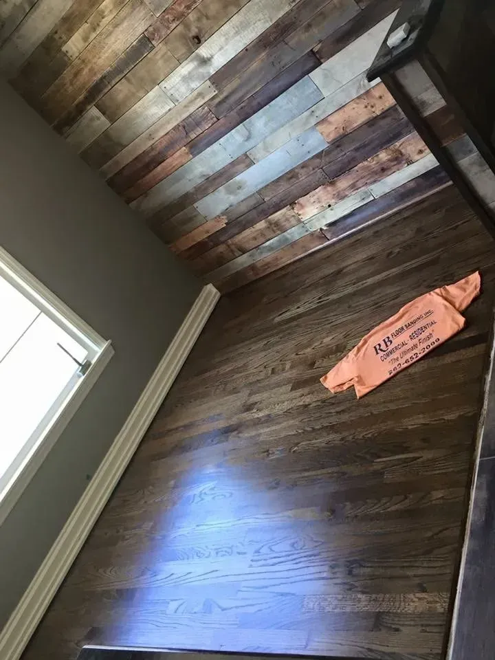 Wood paneled ceiling and hardwood floor, window to the left, and a brown object on the floor.