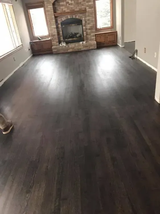 Dark wood floor in living room with fireplace and two cabinets.