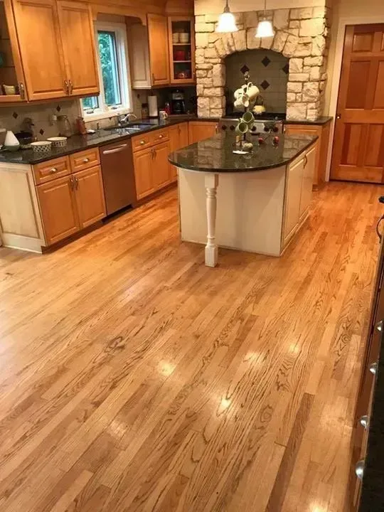 Kitchen with hardwood floors, light wood cabinets, granite countertops, and an island.