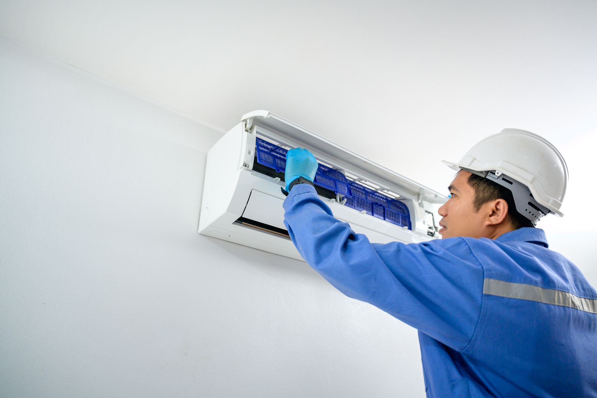 A professional technician performs an air conditioning installation on a modern wall-mounted unit