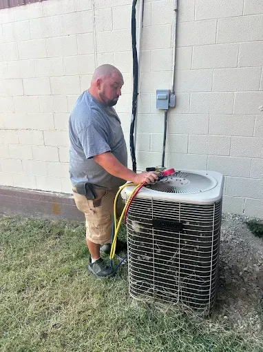 Woman in straw hat smiles, holding wine glass near a lake.