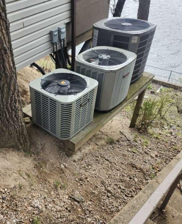 Woman in straw hat smiles, holding wine glass near a lake.