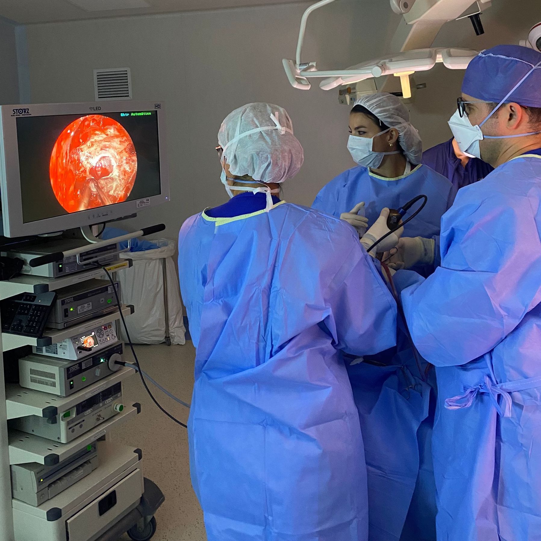 Un grupo de cirujanos en una sala de operaciones mirando un monitor.
