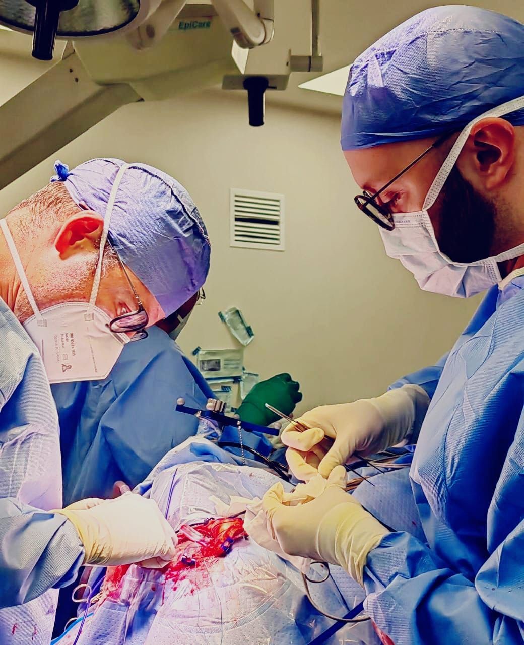 Dos cirujanos están operando a un paciente en un quirófano.