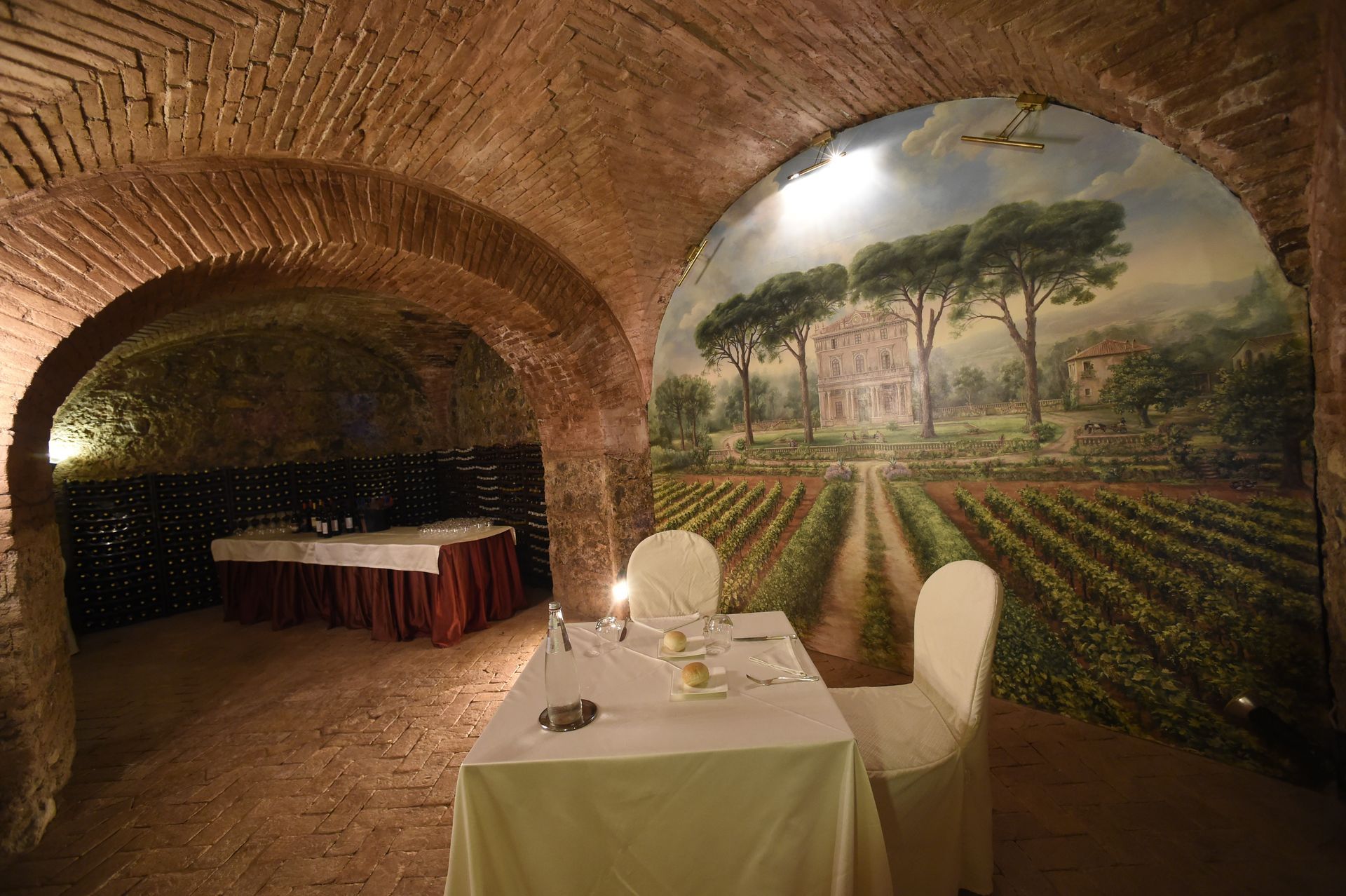 Un tavolo e sedie in una cantina con il dipinto di un vigneto sul muro.