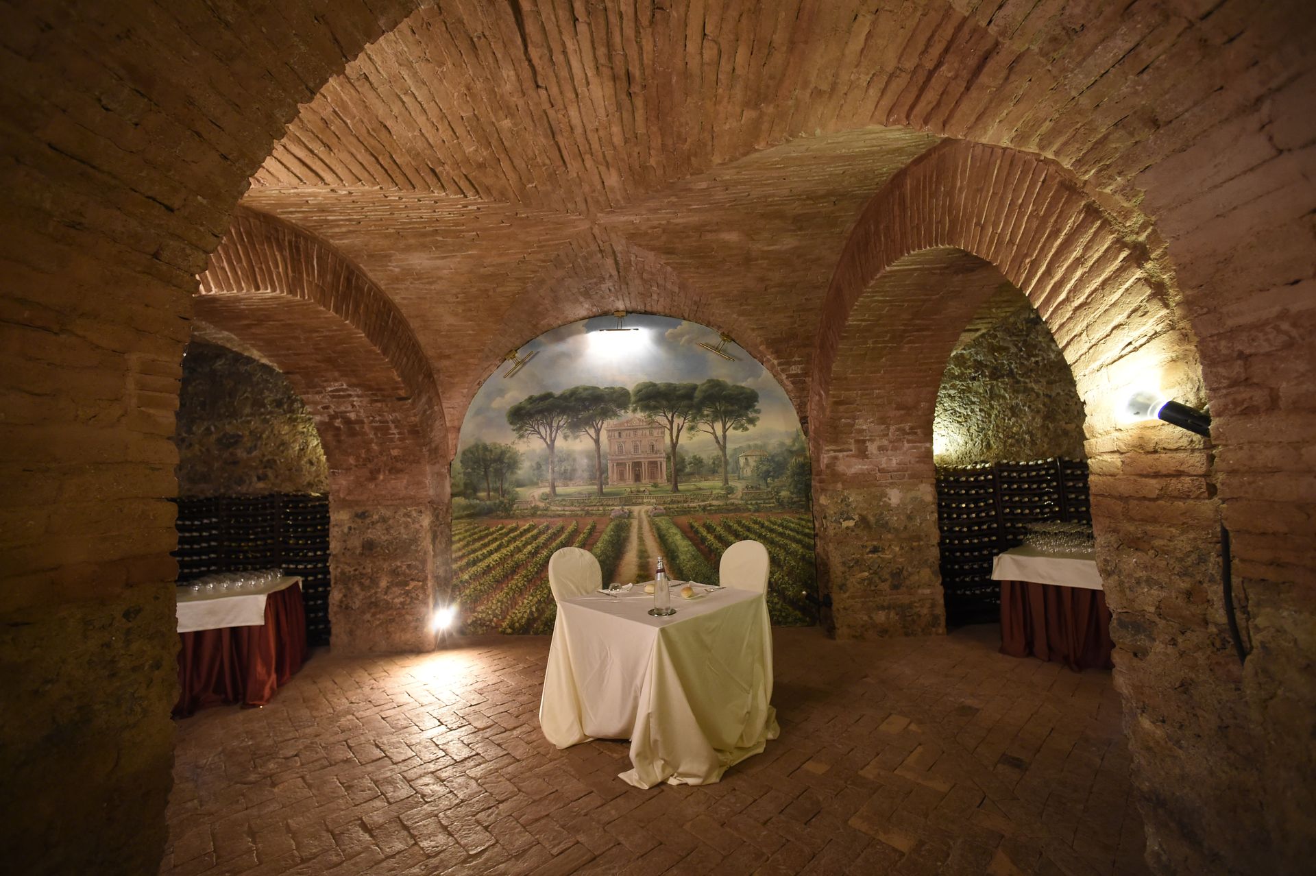 Un tavolo e sedie in una stanza buia con un dipinto sul muro.